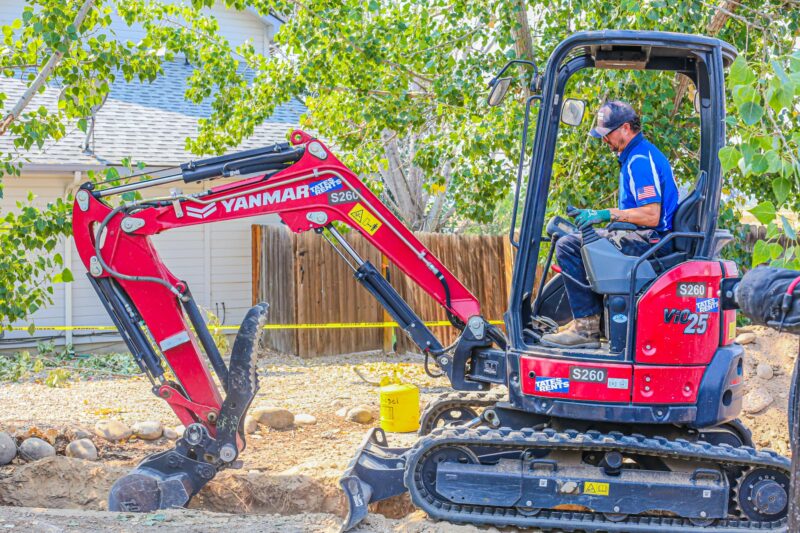 plumbing solutions of idaho tech using excavator on residential property.