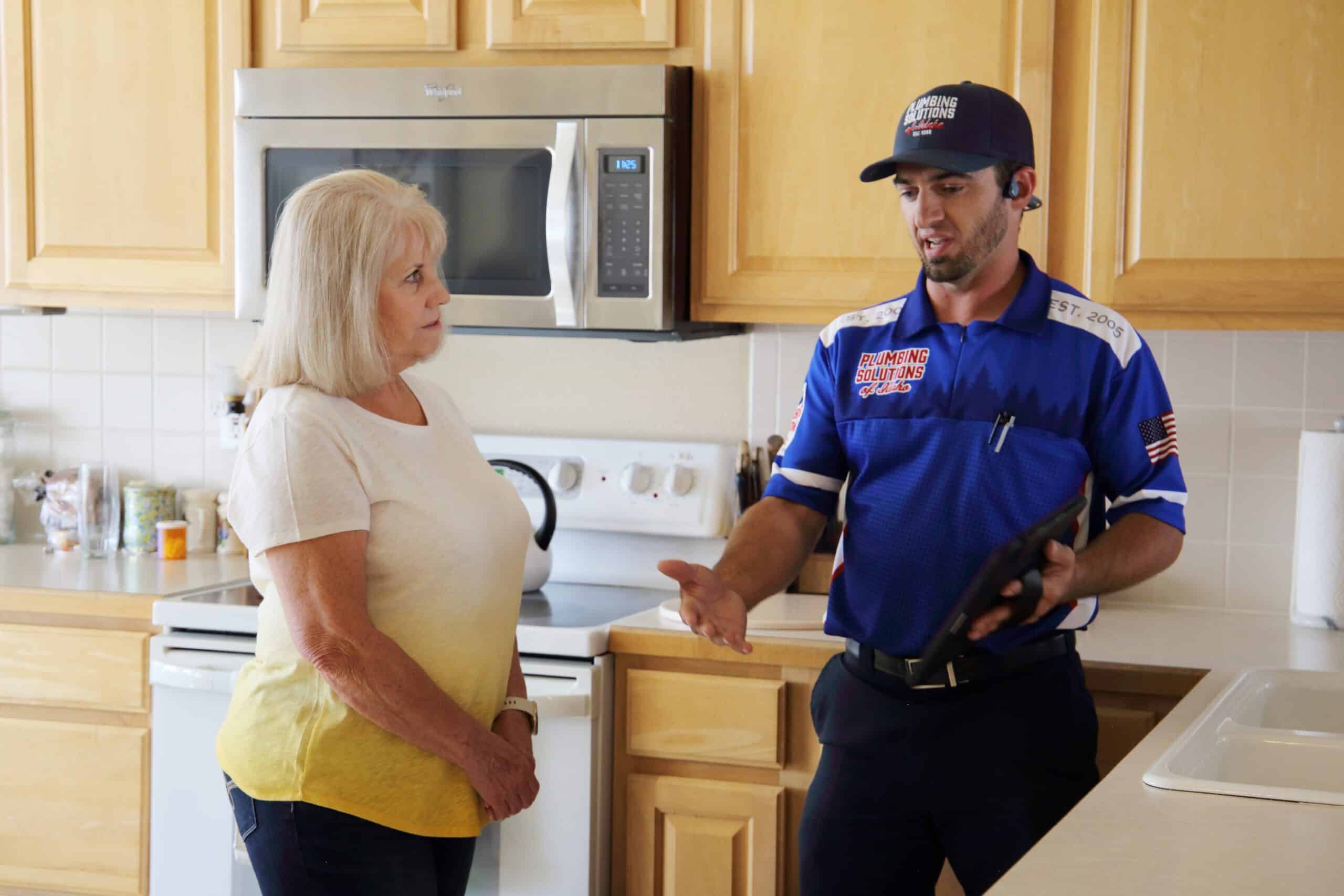 Plumber helping client walk through plumbing service in kitchen in Boise, ID