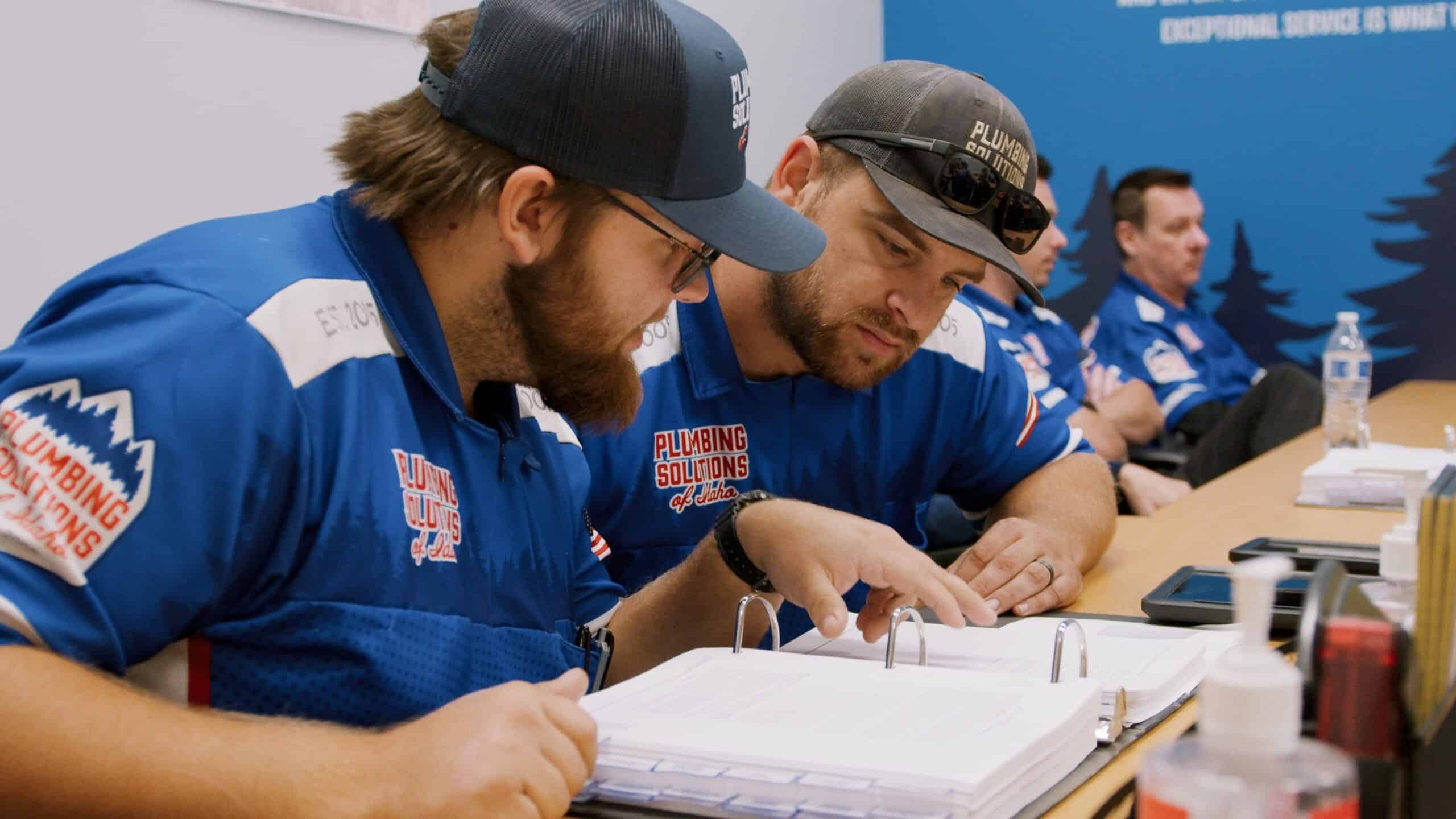 Workmen reading over project notes in warehouse