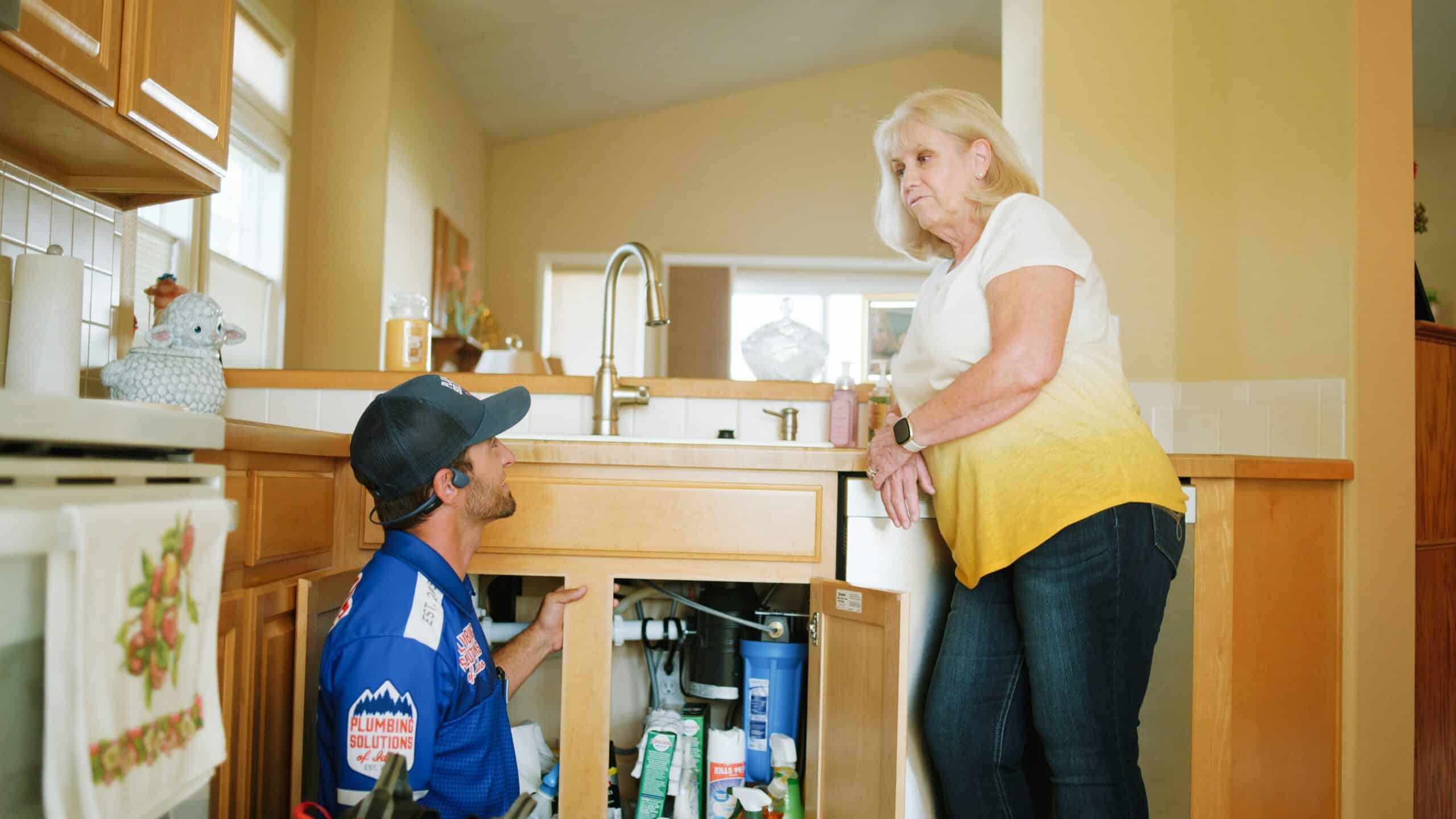 Plumber helping client walk through plumbing service in kitchen in Boise, ID